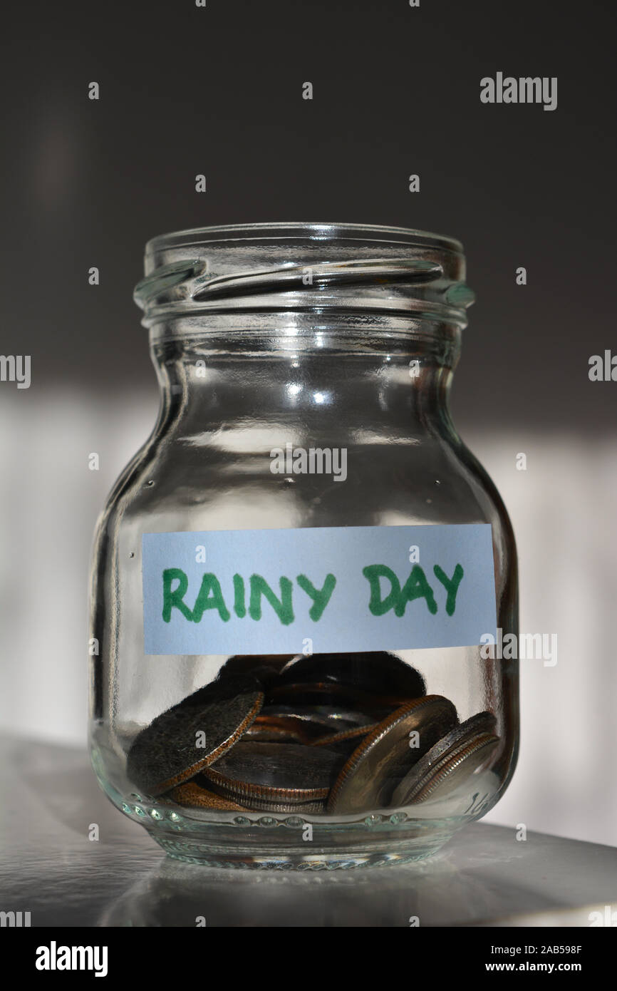 Épargner pour un jour de pluie, un bocal en verre avec des pièces Banque D'Images