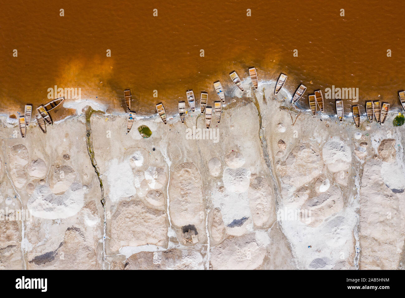 Vue aérienne de petits bateaux pour la collecte du sel au Lac Rose Lac Retba ou Lac Rose au Sénégal. Photo faite par drone depuis au-dessus. Le paysage naturel de l'Afrique Banque D'Images