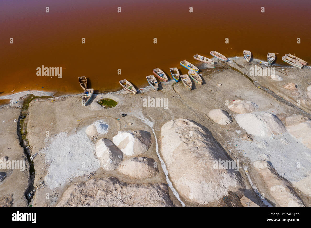 Vue aérienne de petits bateaux pour la collecte du sel au Lac Rose Lac Retba ou Lac Rose au Sénégal. Photo faite par drone depuis au-dessus. Le paysage naturel de l'Afrique Banque D'Images