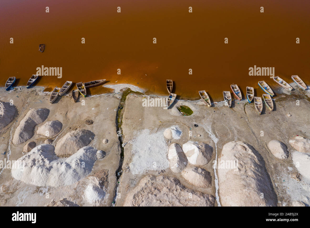 Vue aérienne de petits bateaux pour la collecte du sel au Lac Rose Lac Retba ou Lac Rose au Sénégal. Photo faite par drone depuis au-dessus. Le paysage naturel de l'Afrique Banque D'Images