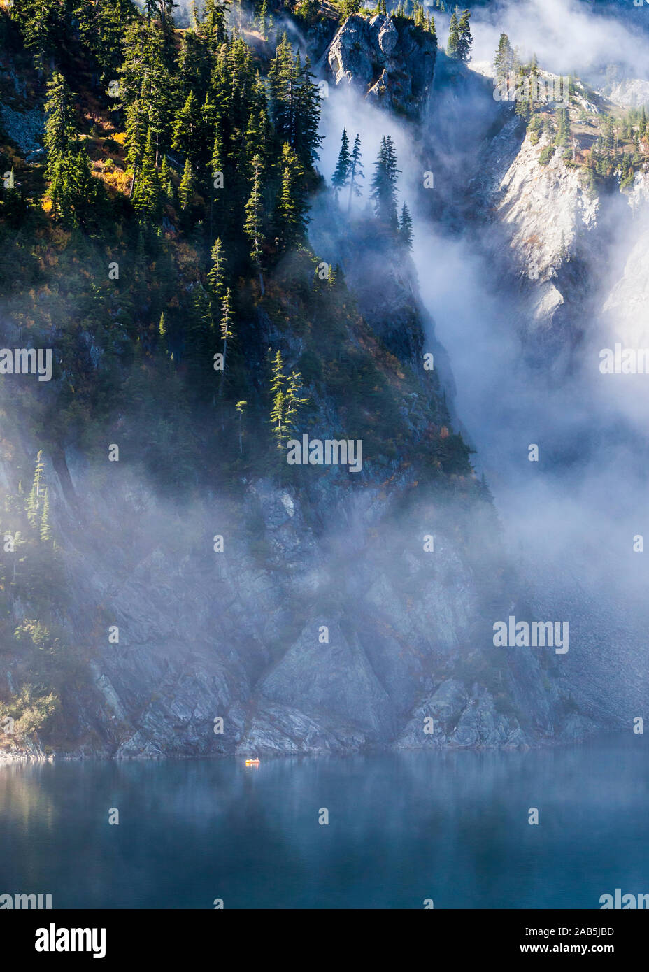 Un homme dans un petit radeau pneumatique de l'aviron sur le lac de la neige au-dessus de Snoqualmie Pass dans la partie centrale de la chaîne des Cascades dans l'État de Washington, USA. Banque D'Images