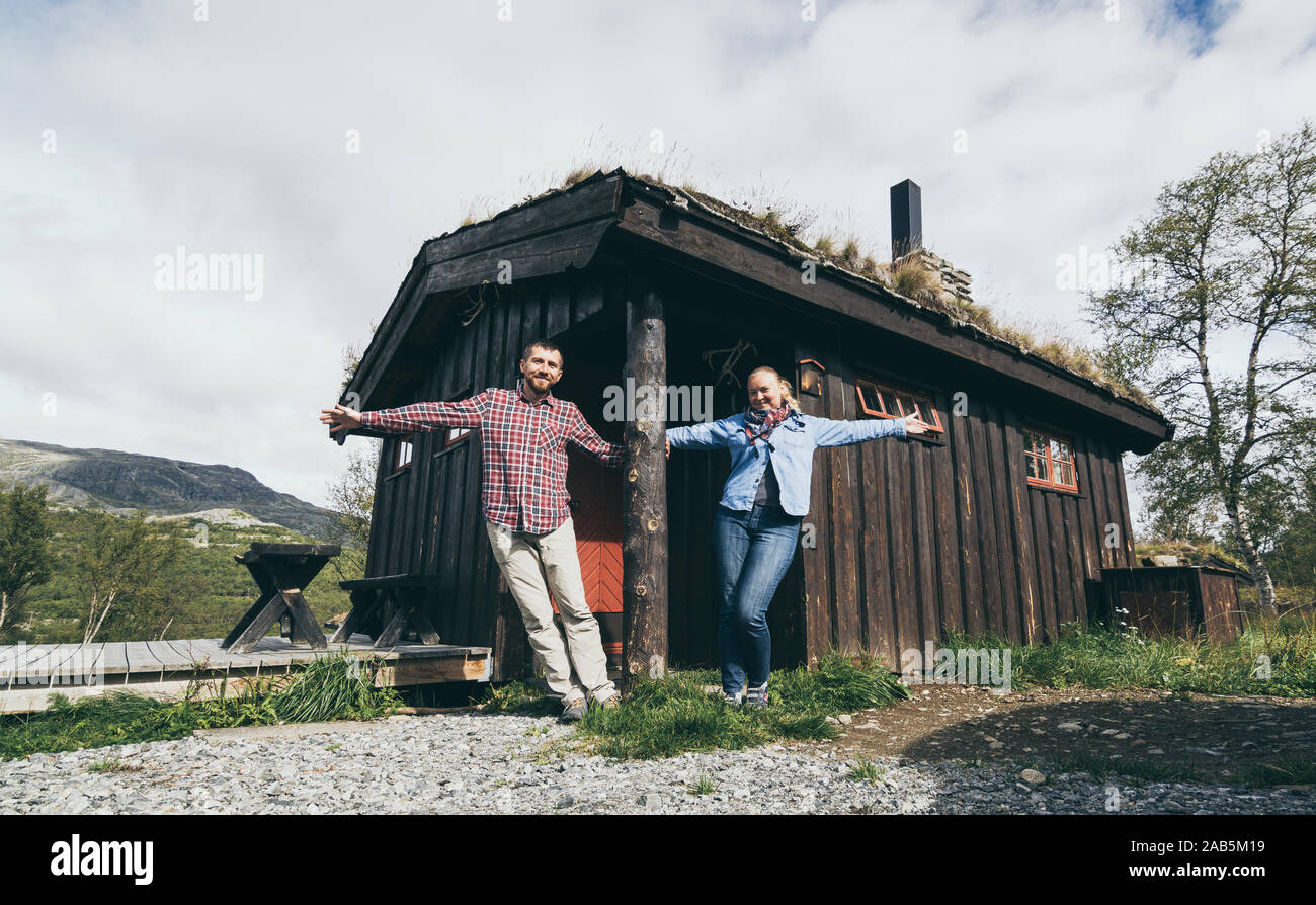 Jeune couple debout à côté de la maison en bois dans le parc national de Jotunheimen, Norvège Banque D'Images