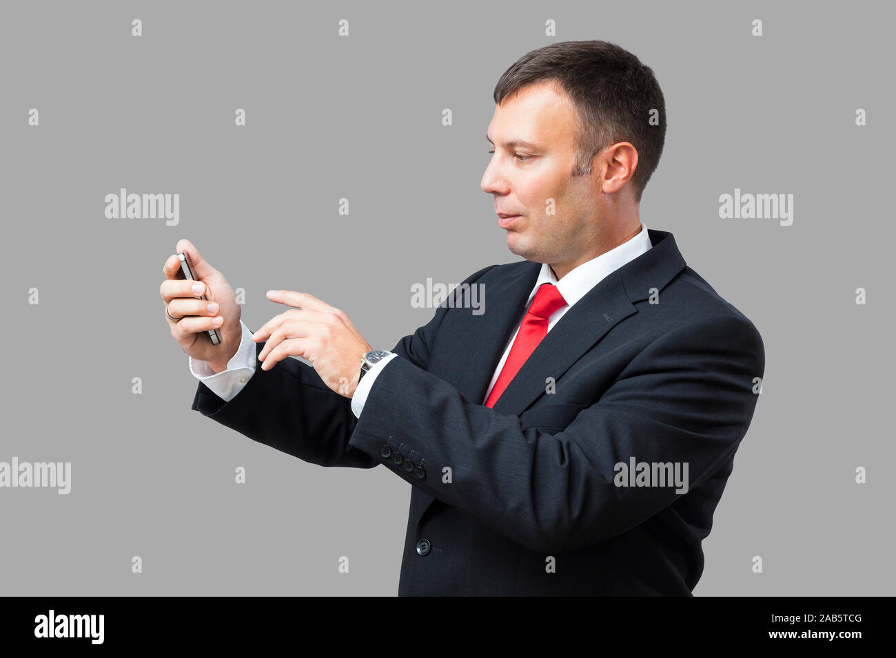 Un Geschaeftsmann, der ein Mobiltelefon in der Hand haelt Banque D'Images