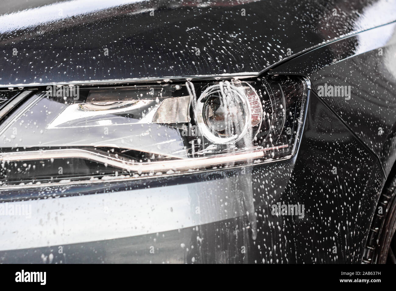 Gouttes d'eau et de la mousse sur la voiture lumière dans la station de lavage vehcle. Concept automobile de nettoyage, la pollution de l'eau souterraine. Banque D'Images