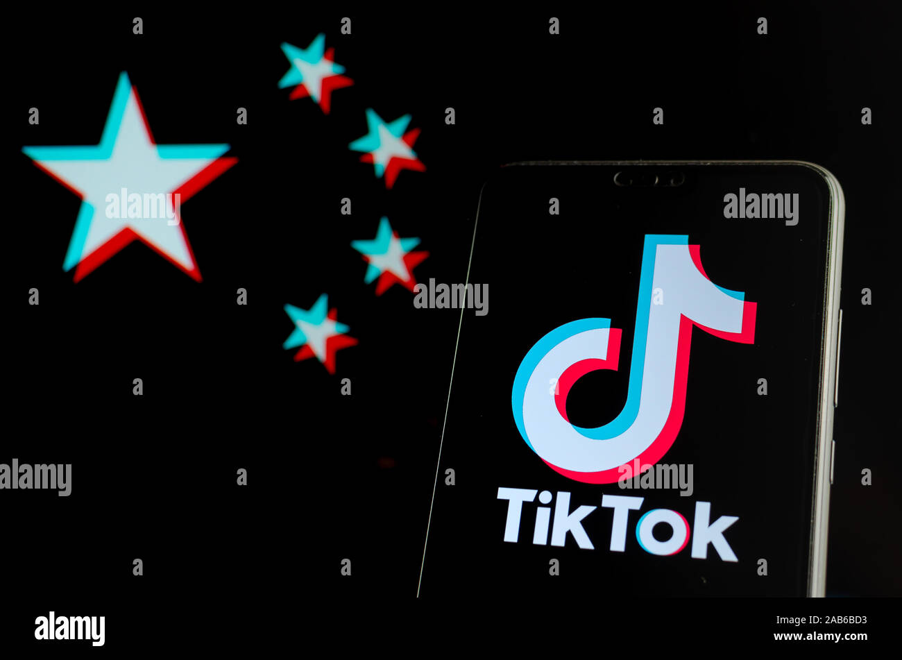 TikTok logo sur le smartphone et floues drapeau de la Chine à l'effet split-RVB sur l'écran de l'ordinateur portable derrière elle. Concept pour la popularité. Banque D'Images