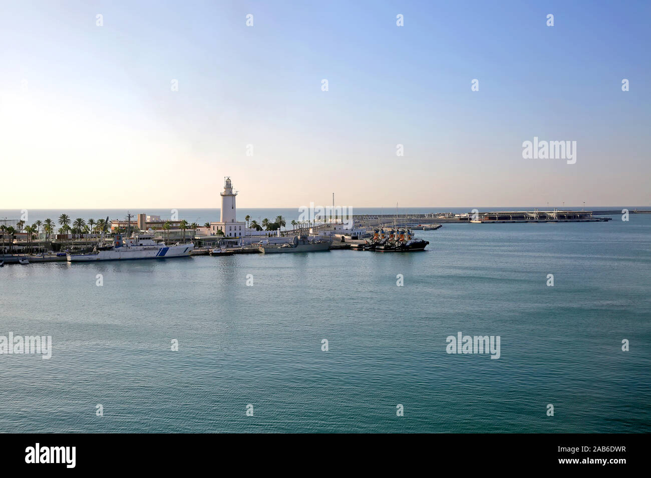 Le Port de Malaga, avec quelques petits navires à quai et le phare sur la jetée, l'Andalousie, Sud de l'Espagne. Banque D'Images