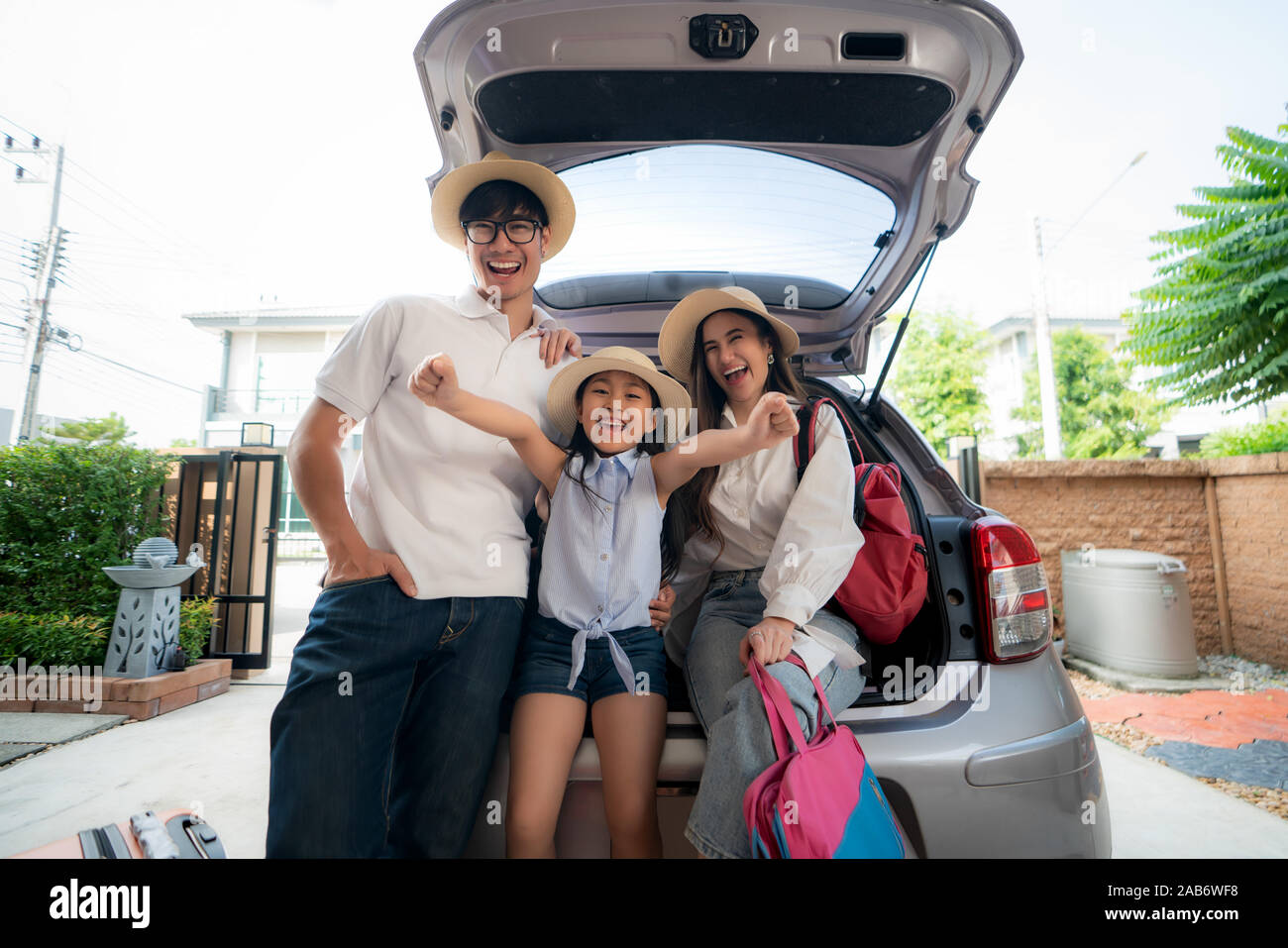 Portrait de famille asiatique avec le père, la mère et la fille a l'air heureux tandis que la préparation de valise dans une voiture pour les vacances. Tourné à la Chambre garage. Banque D'Images