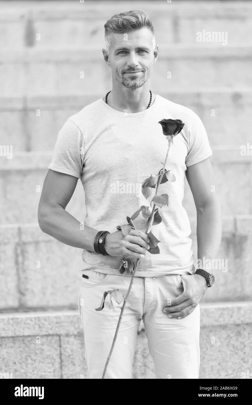 Heureux jour femmes à toutes les jolies femmes. Homme barbu tenant womens day flower au printemps. Bel homme à la rose pour célébrer la Journée de la femme. 8 mars ou internationales de femmes. Banque D'Images