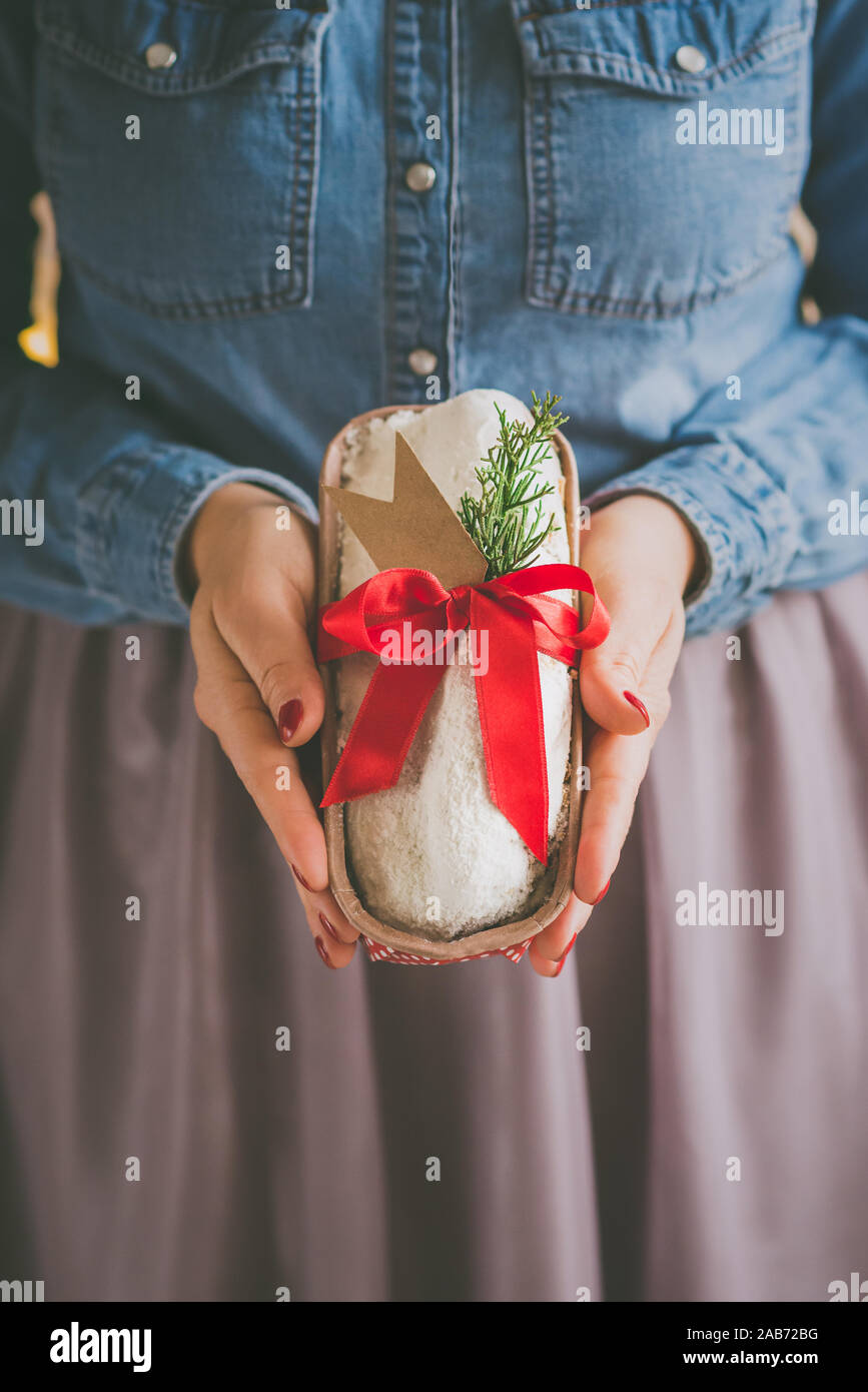 Close up of woman's hands holding des stollen christmas cake, enveloppé comme un cadeau. Focus sélectif. Banque D'Images