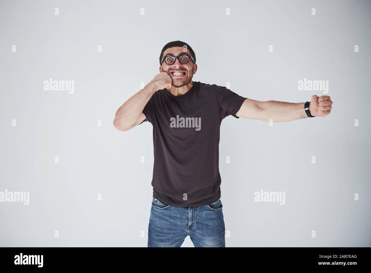 Un jeune homme dans les tenues sur le fond frappé lui-même sur le poing dans la figure. Le concept d'auto-punition pour leurs propres erreurs Banque D'Images