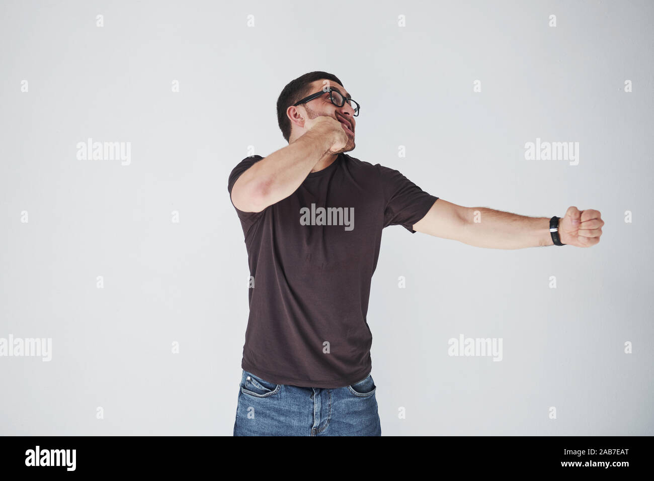 Un jeune homme dans les tenues sur le fond frappé lui-même sur le poing dans la figure. Le concept d'auto-punition pour leurs propres erreurs Banque D'Images