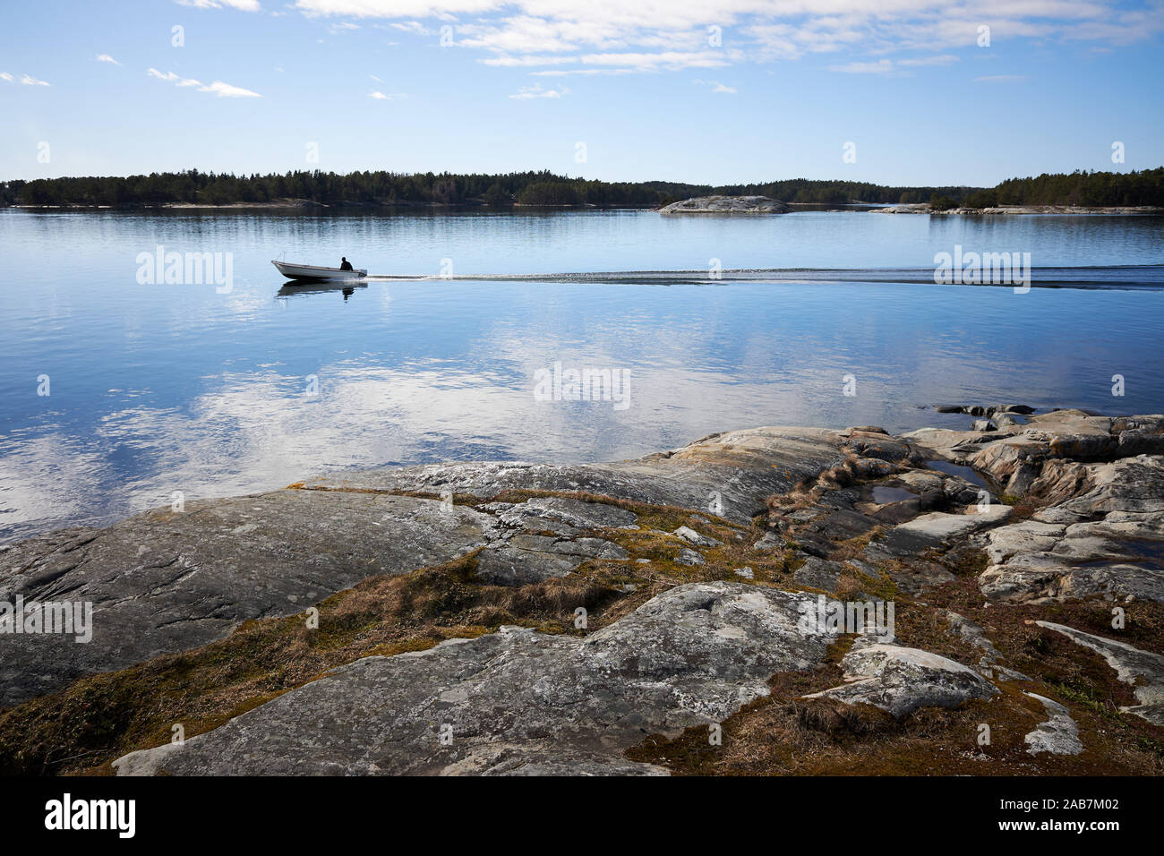 Petit bateau de pêche sur l'eau de mer. Beaux rochers sur la rive de la mer Baltique dans Kassnäs e, île Kemiö en Finlande. Banque D'Images Petit bateau de pêche sur l'eau de mer. Beaux rochers sur la rive de la mer Baltique dans Kassnäs e, île Kemiö en Finlande. Banque D'Images