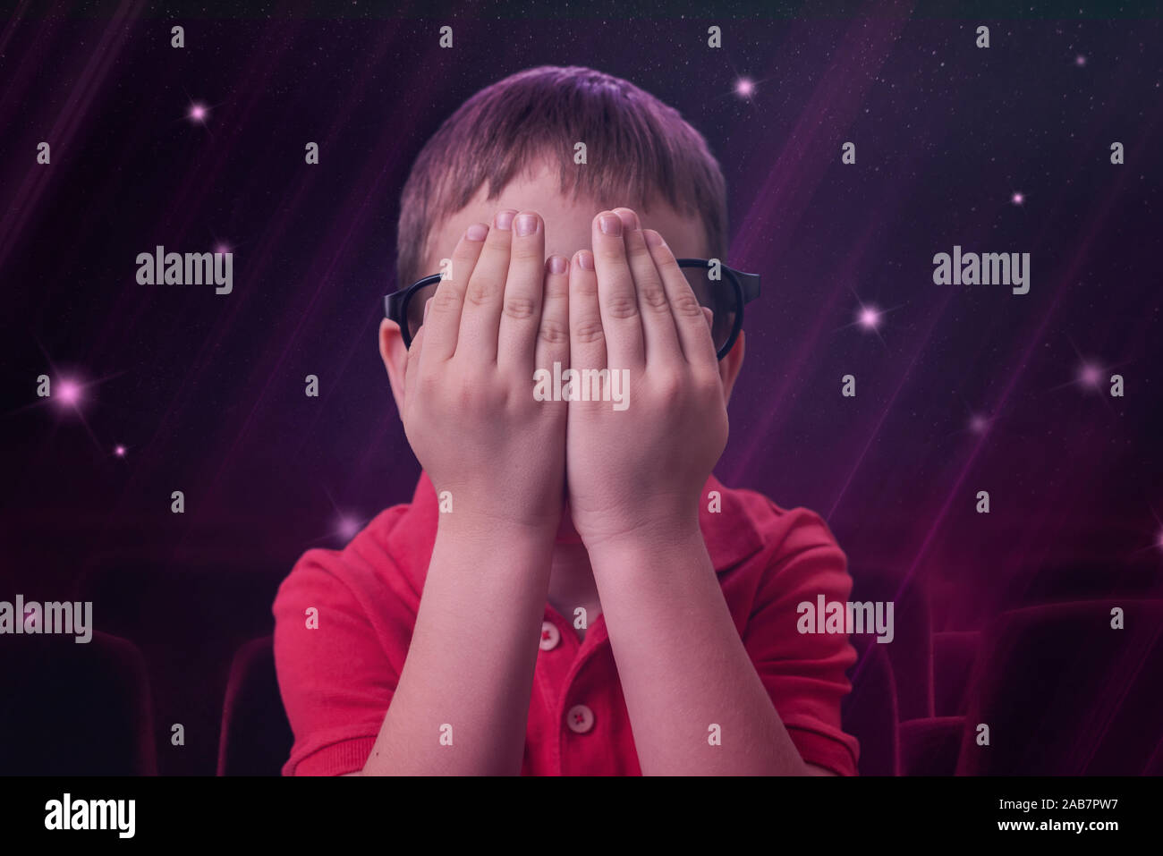 Le garçon garde ses mains sur ses yeux, car c'est un effrayant scène du film. Banque D'Images