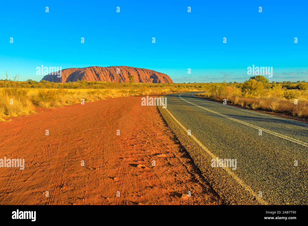 Route menant à Uluru (Ayers Rock) à la couleur éclatante de coucher du soleil, Outback, Parc National d'Uluru-Kata Tjuta, UNESCO, Territoire du Nord, Australie, Pacifique Banque D'Images