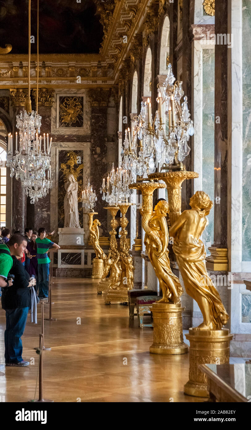 Grande vue portrait de visiteurs d'admirer la ligne de statues dorées et est tenue en place de la feuille d'or crystal chandeliers dans la célèbre Galerie des Glaces... Banque D'Images