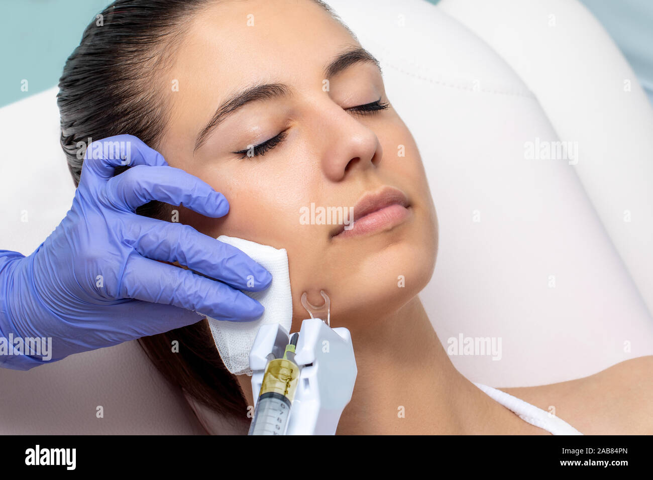 Faire cometic thérapeute plasma ascenseur facial sur jeune femme. Gants en latex avec l'application de la technologie de micro-aiguille sur le menton. Banque D'Images