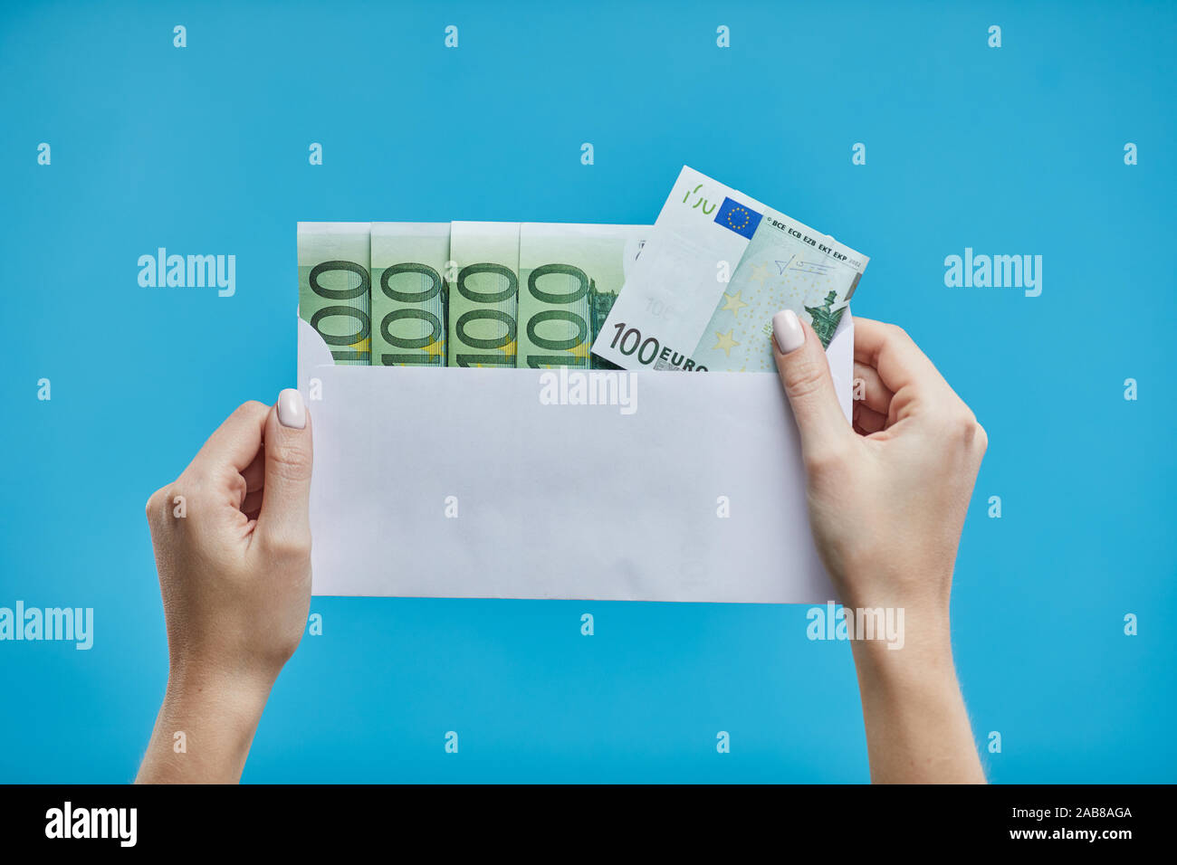 Les mains tenant les billets en euros sur un fond bleu. Euro argent euro fond de trésorerie. Banque D'Images