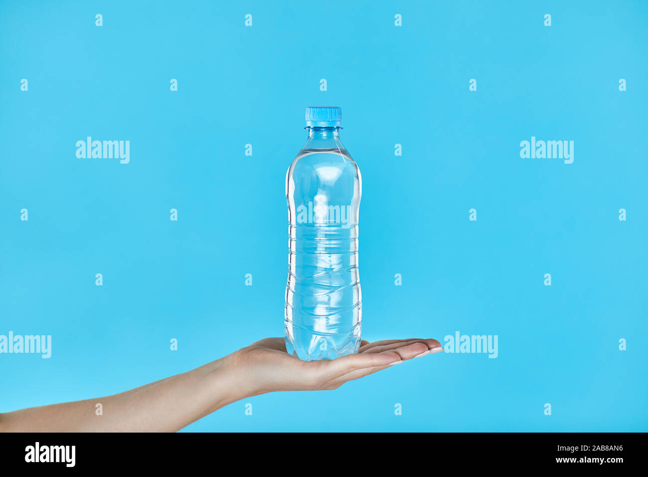 Femme mains tenant une bouteille d'eau sur un fond bleu. Concept pour la Vie saine Banque D'Images