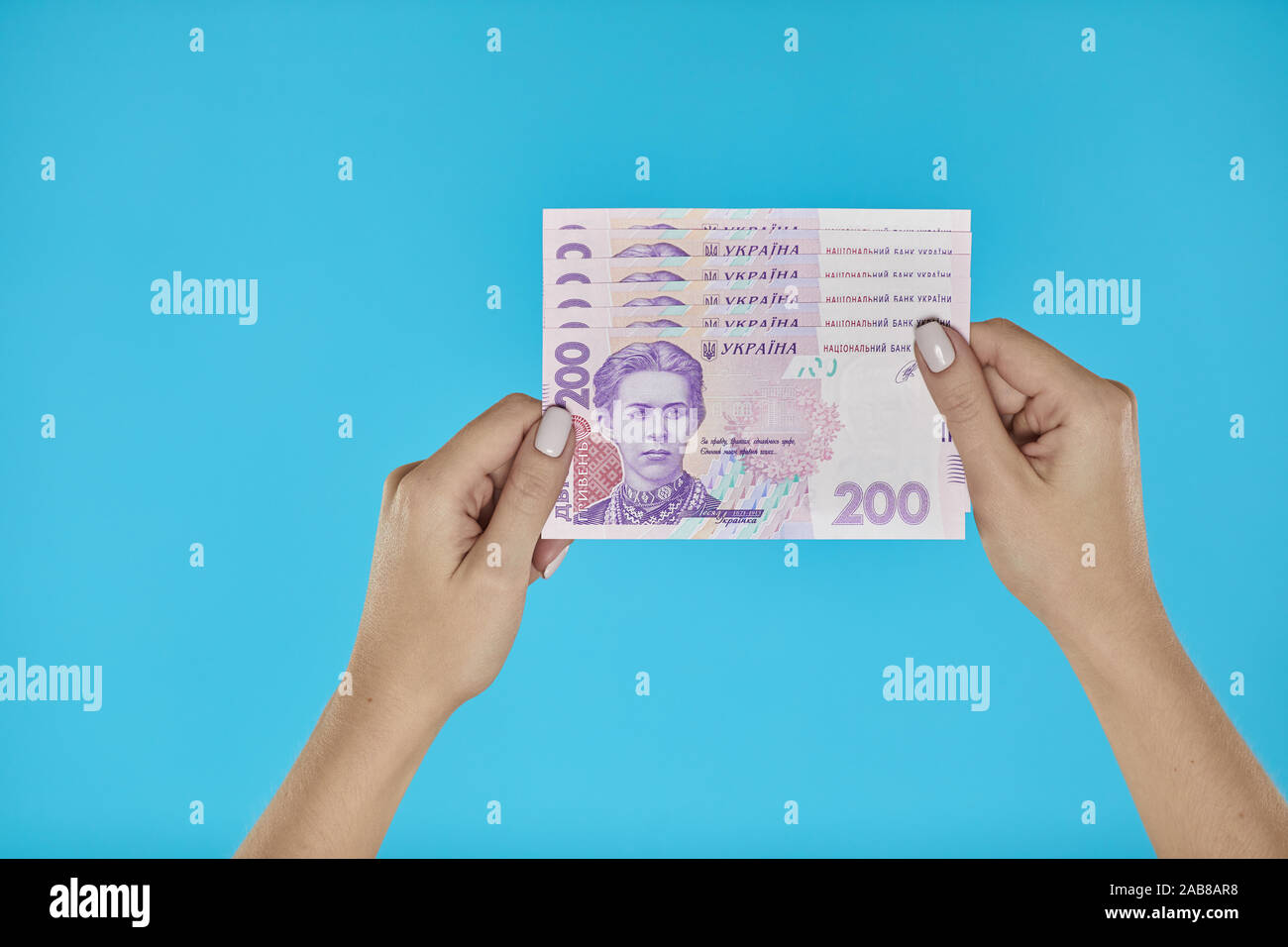 L'argent comptant. Les mains tenant les billets de l'Ukraine sur fond bleu Banque D'Images
