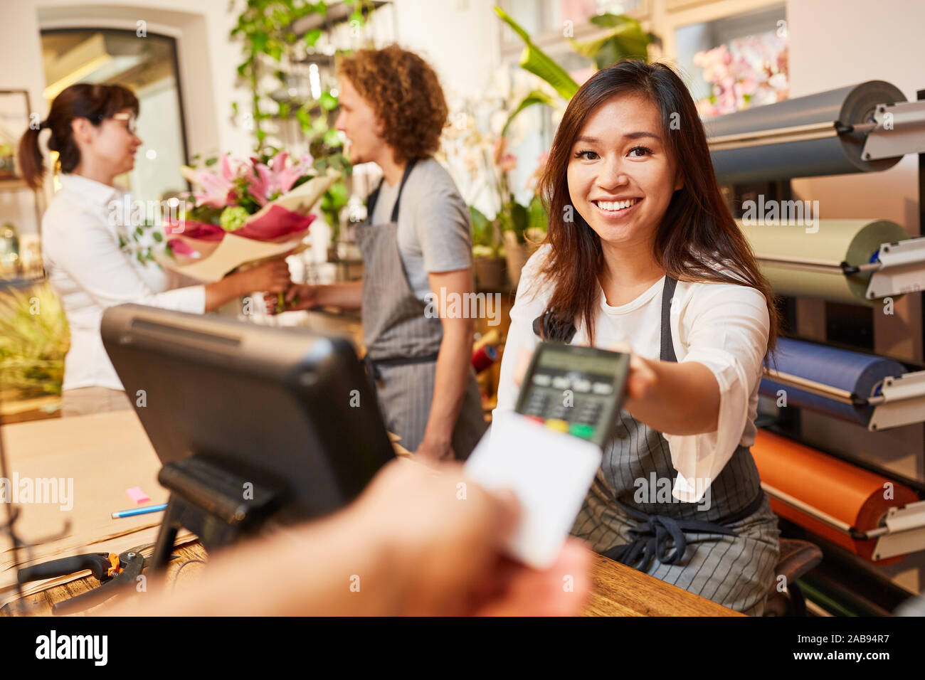 Jeune femme comme caissier prend la carte de crédit pour payer à la caisse Banque D'Images