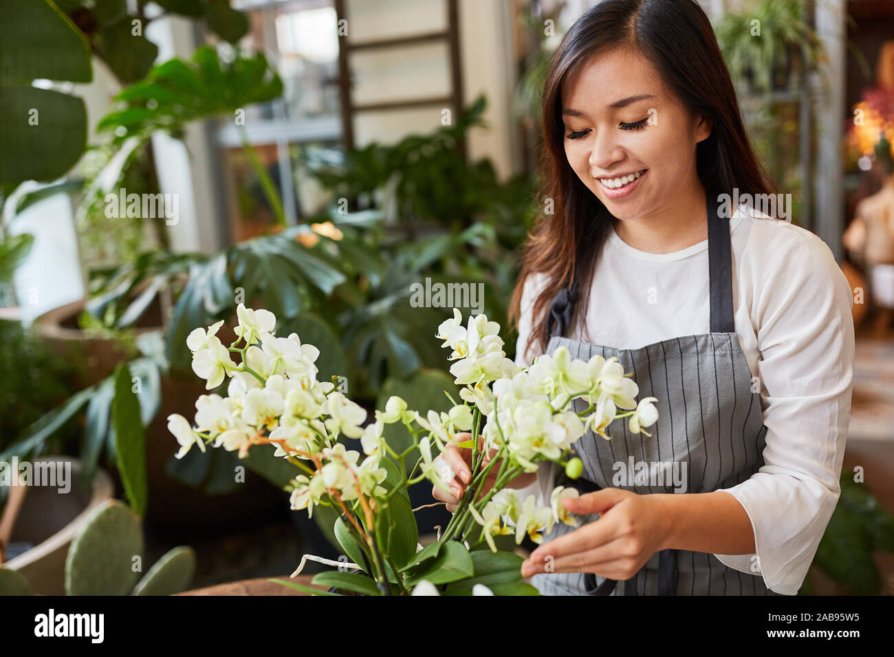 Fleuriste asiatique dans la formation avec un arrangement floral Banque D'Images
