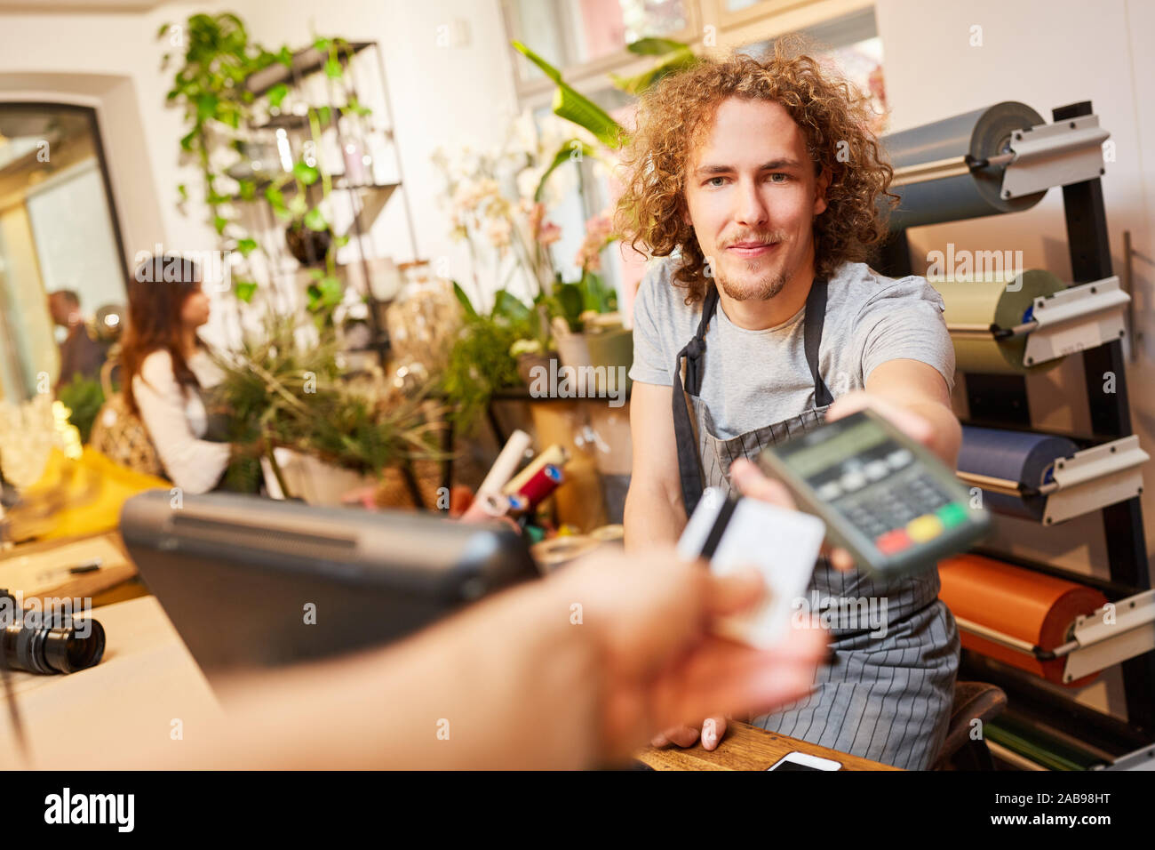 Donne la main la carte de crédit pour payer à la caisse dans le magasin de fleurs Banque D'Images