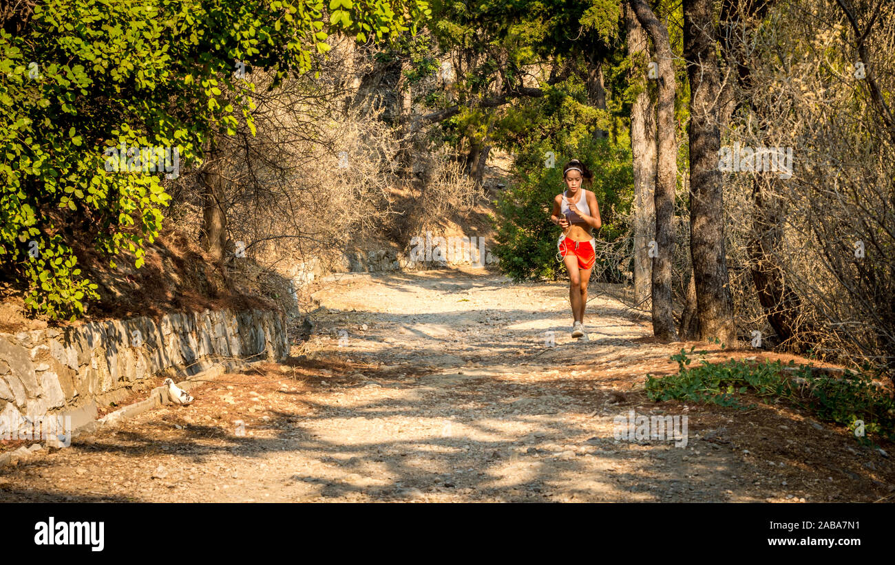 L'adolescent au short rouge et blanc sur la saleté de jogging tanktop sentier à partir de l'avant à Athènes Grèce Banque D'Images