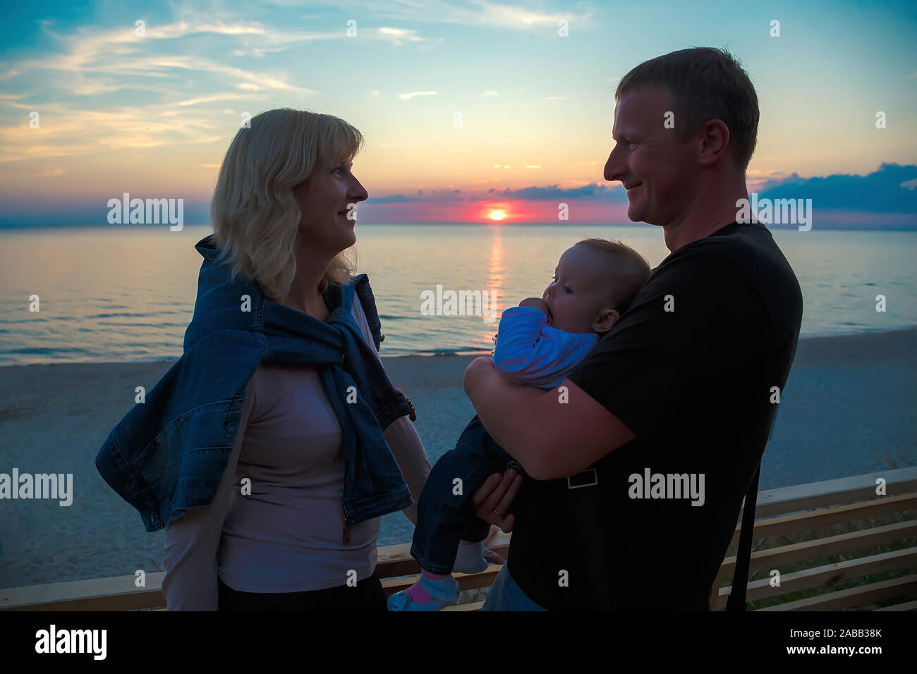 Famille avec un jeune enfant sur les rives de la mer Baltique en regardant le coucher du soleil. Banque D'Images