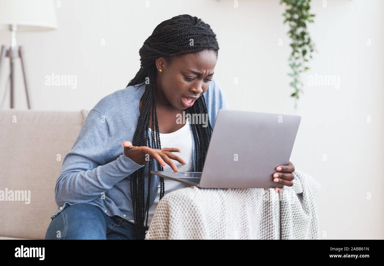 Afro girl frustrés des problèmes avec l'ordinateur portable à la maison Banque D'Images