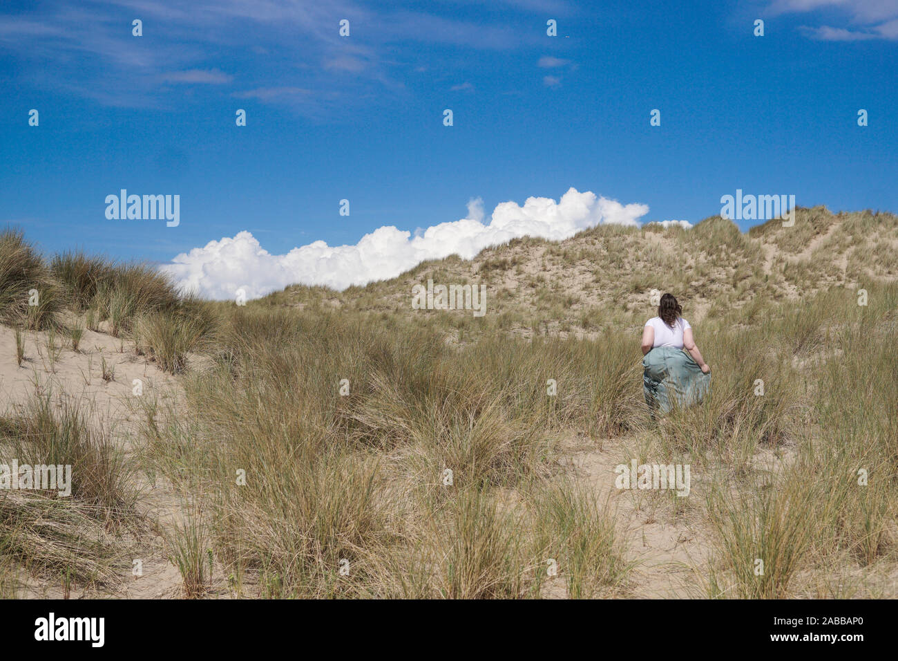 Femme marche dans les dunes de sable sur un jour de vent, Benar Beach, Barmouth, Gwynedd, Pays de Galles, Royaume-Uni Banque D'Images