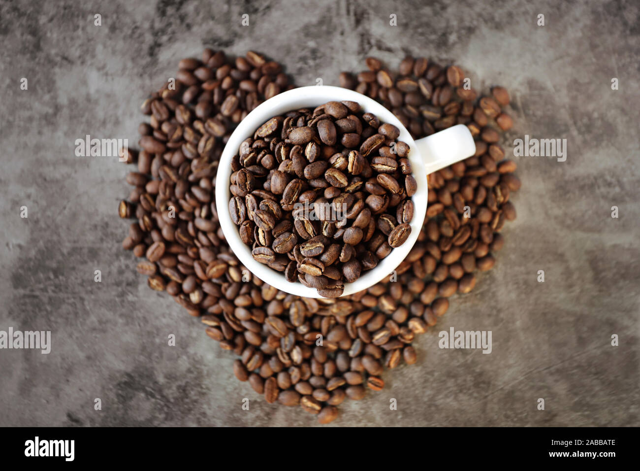 Tasse de café torréfiés sur un arrangement en forme de coeur de grains de café Banque D'Images