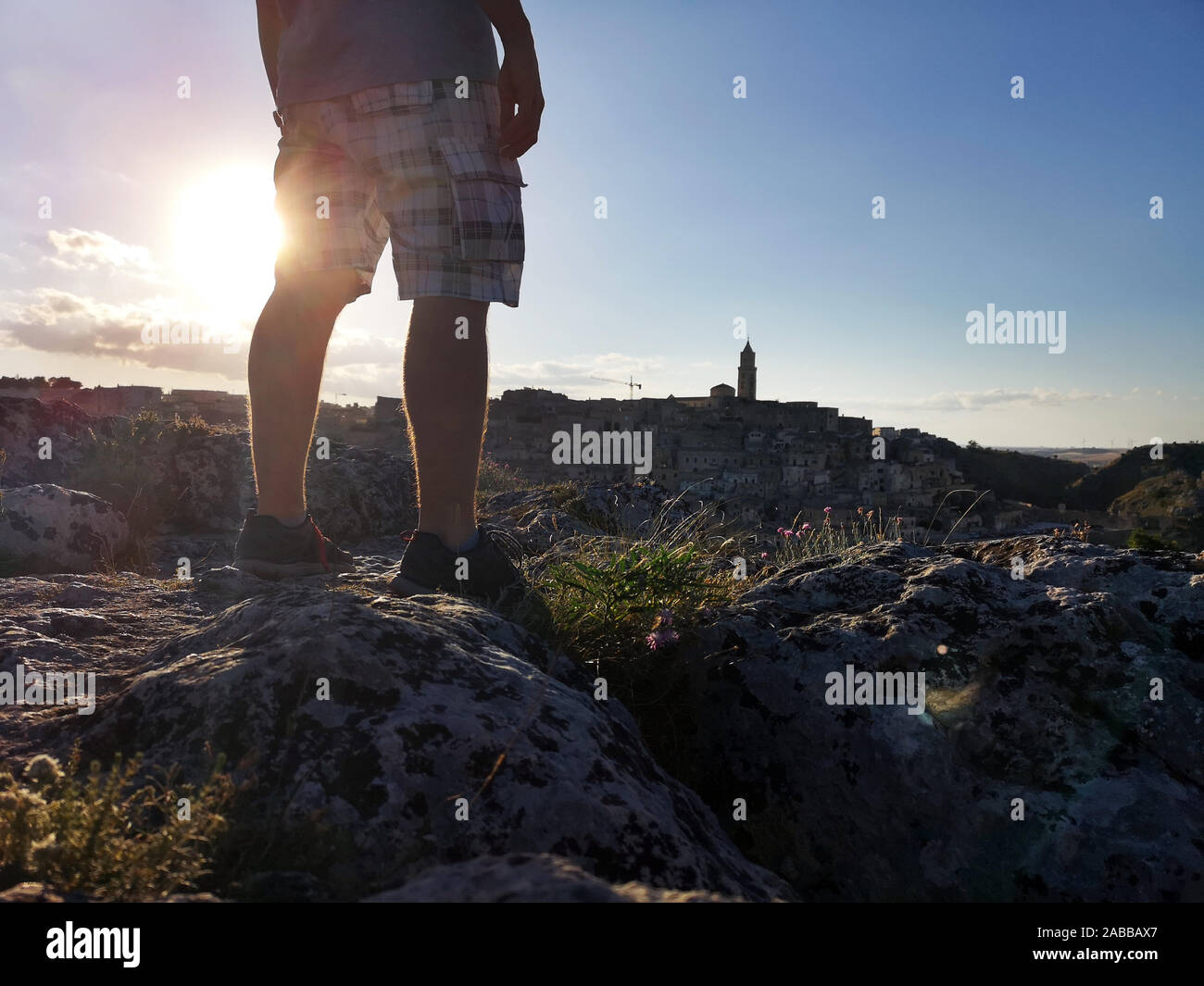 Homme debout sur des rochers au coucher du soleil, Matera, Basilicate, Italie Banque D'Images