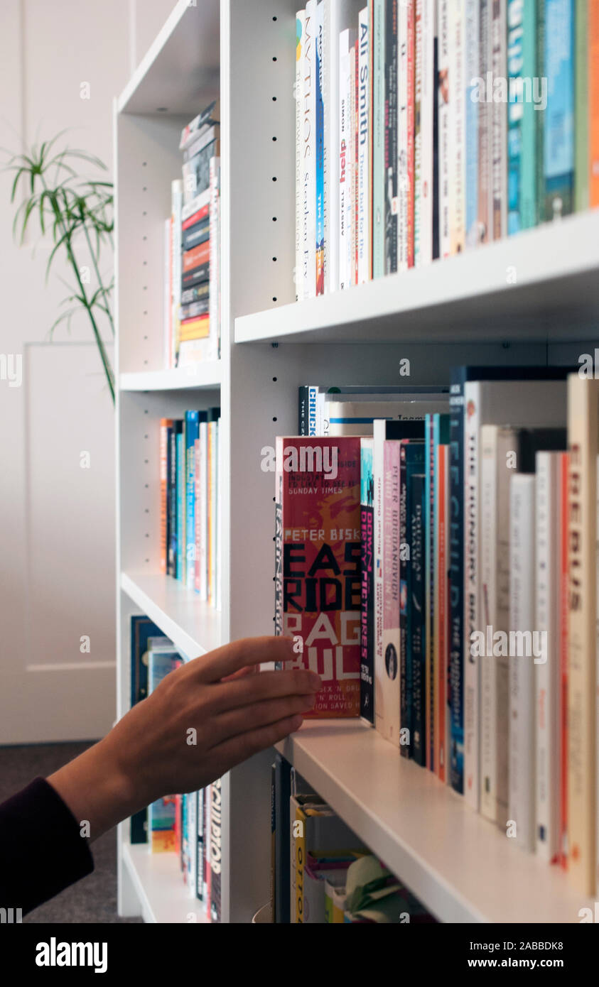 Choisir un livre - une personne choisir leur prochaine lecture forment une étagère pleine de livres. Banque D'Images