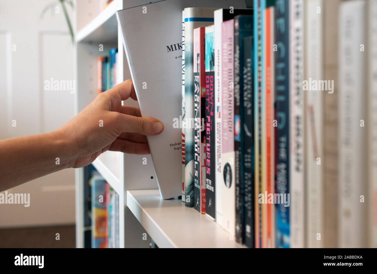Choisir un livre - une personne choisir leur prochaine lecture forment une étagère pleine de livres. Banque D'Images