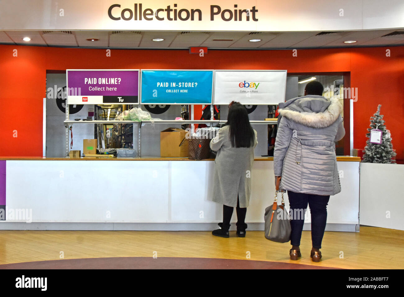 Commerce de détail de l'intérieur à Argos catalogue shopping store vue arrière de clients d'être servis au comptoir du point de collecte à Noël England UK Banque D'Images