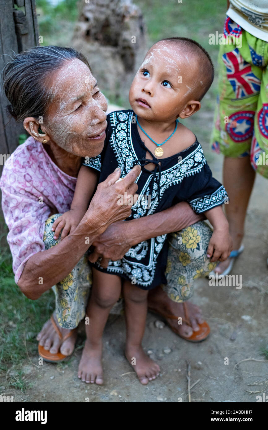 Grand-mère et petit-fils avec de la poudre de visage (crème solaire) accueillent les visiteurs dans le village le long de la chaîne de la rivière Chindwin, dans le nord-ouest de Myanmar (Birmanie) Banque D'Images