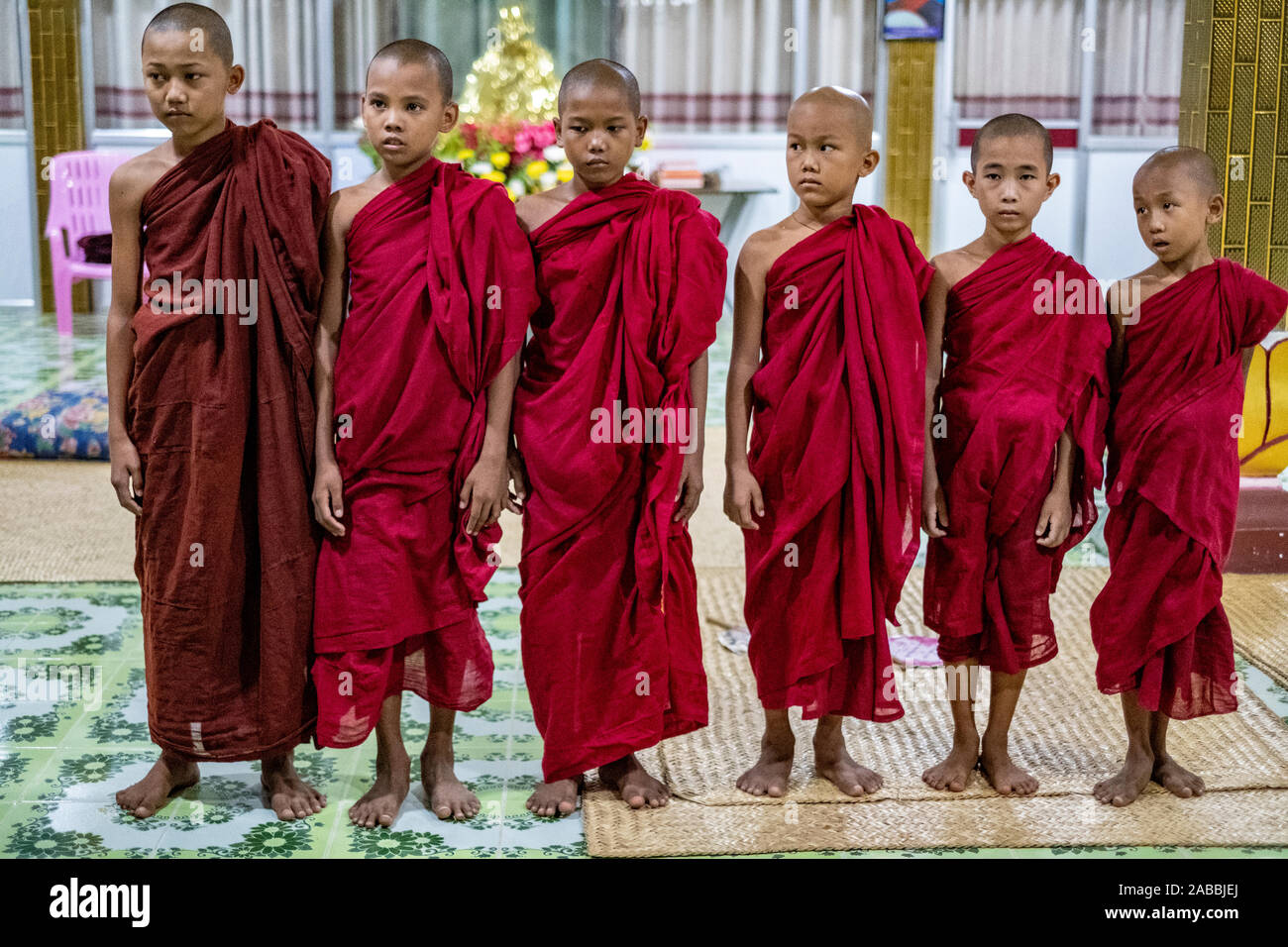 Les jeunes moines bouddhistes avec le crâne rasé et scarlet robes lors d'une ligne à un monastère le long de la rivière Chindwin au Myanmar (Birmanie) Banque D'Images