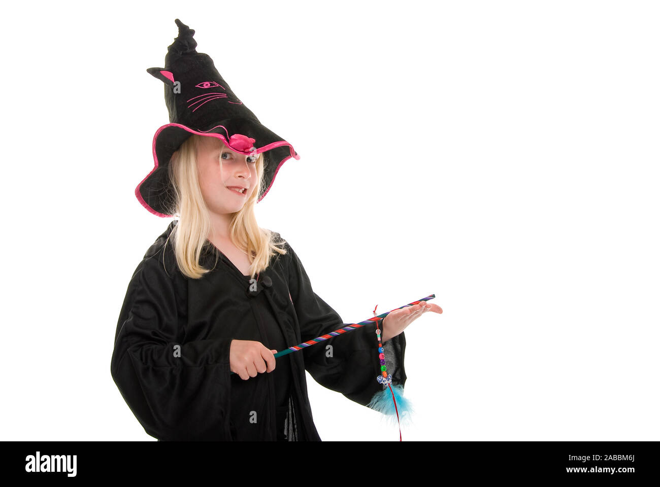 Jeune fille blonde en manteau et un chapeau de sorcière avec baguette. Isolated on white Banque D'Images