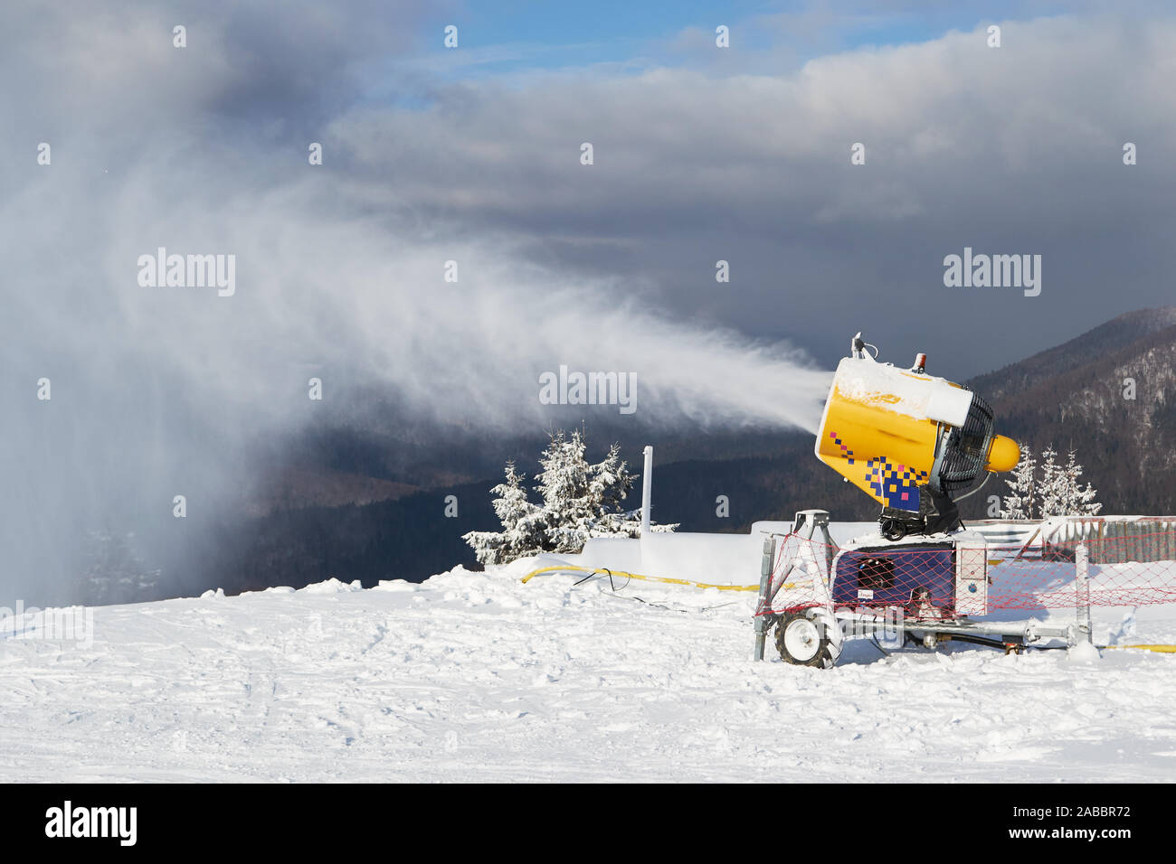 Canon à neige machine au travail sur une piste de ski, domaine skiable à Azuga, région de la Vallée de Prahova, Roumanie. Banque D'Images