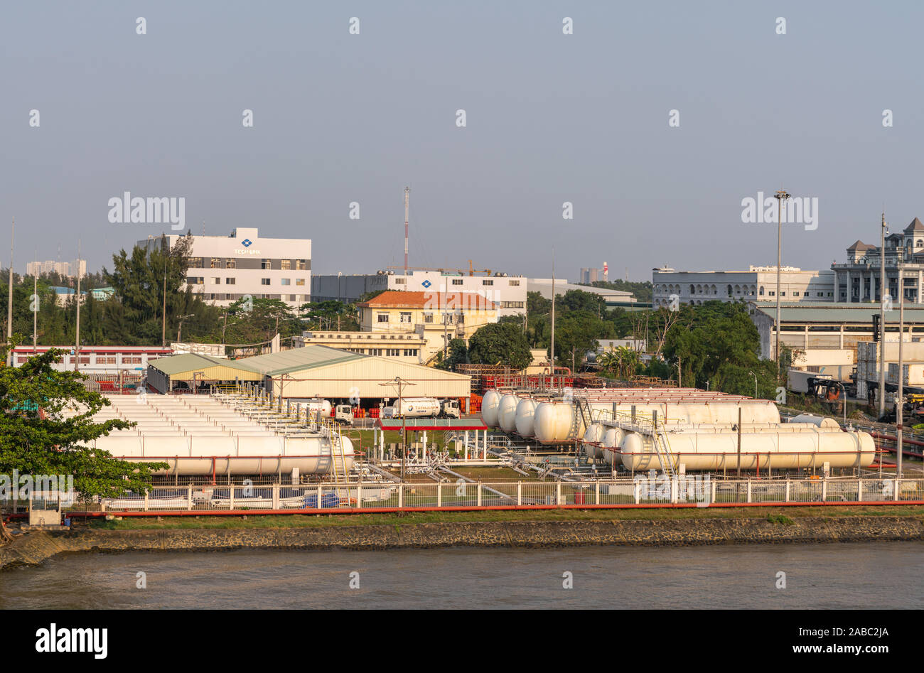 Ho Chi Minh Ville, Vietnam - Mars 13, 2019 : port Totalgaz sur Chanson fleuve Sai Gon au coucher du soleil. Rangées de réservoirs de gaz blanc avec des bâtiments à l'arrière. Les camions sont Banque D'Images