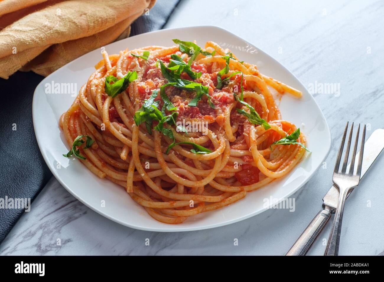 Authentique cuisine italienne bucatini all'amatriciana faite avec des tomates de San Marzano, garnie de basilic frais haché et fromage pecorino romano râpé Banque D'Images