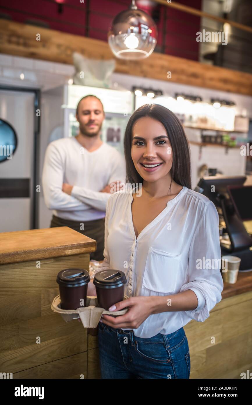 Portrait blouse blanche tenant deux cafés à emporter Banque D'Images