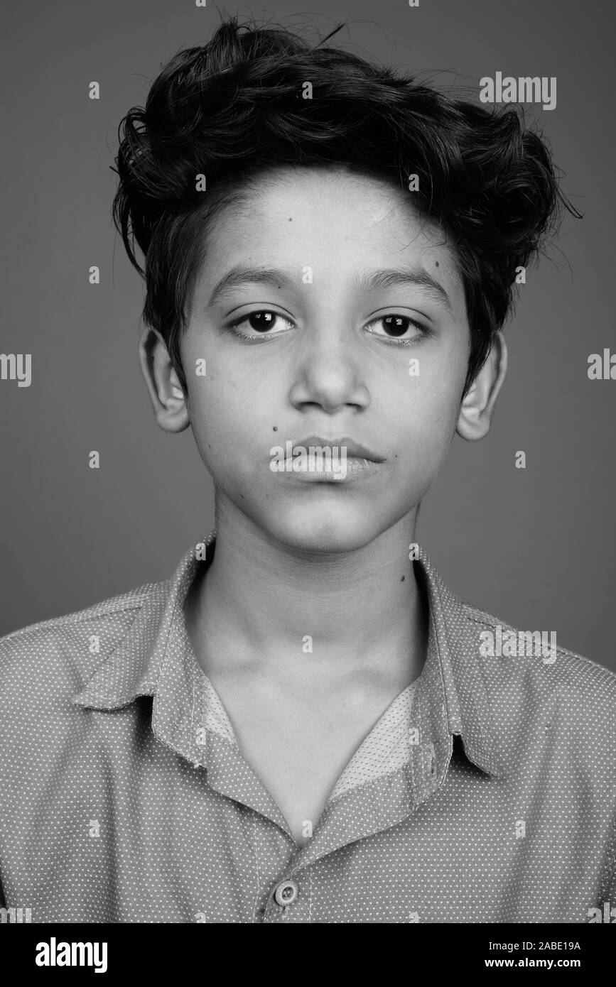 Jeune Indien garçon portant des vêtements chic et décontracté à l'arrière-plan gris Banque D'Images