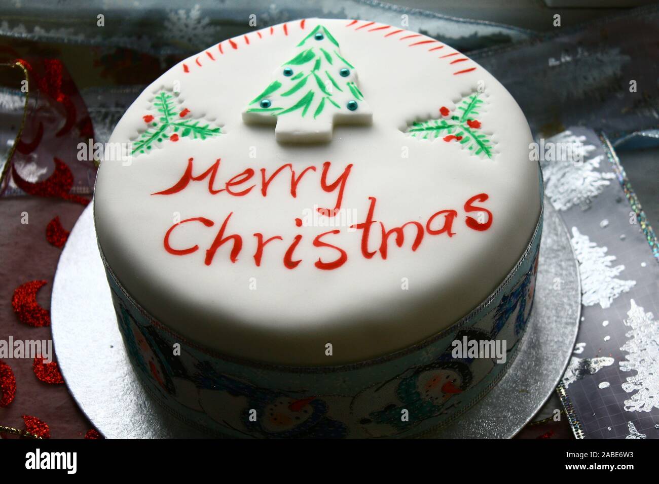 Gâteau avec glaçage blanc Joyeux Noël écrit sur le dessus et un arbre de Noël vert Banque D'Images