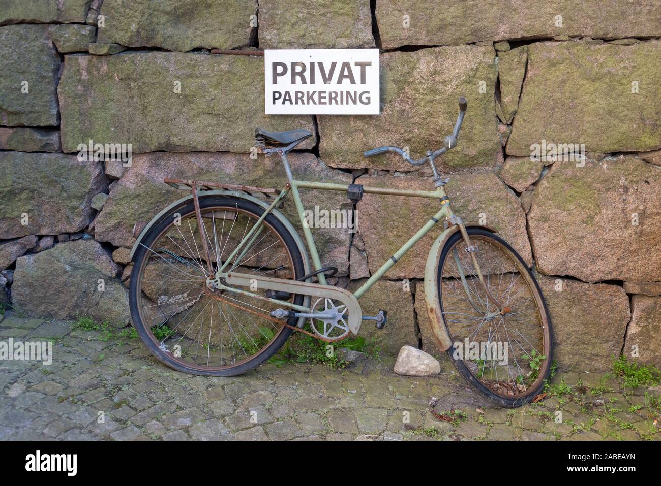 09 juillet 2019, la Suède, Stenungsund : vue sur un vélo rouillé. Il y a un panneau avec l'inscription 'Privatparkplatz' au-dessus. Photo : Stephan Schulz/dpa-Zentralbild/ZB Banque D'Images