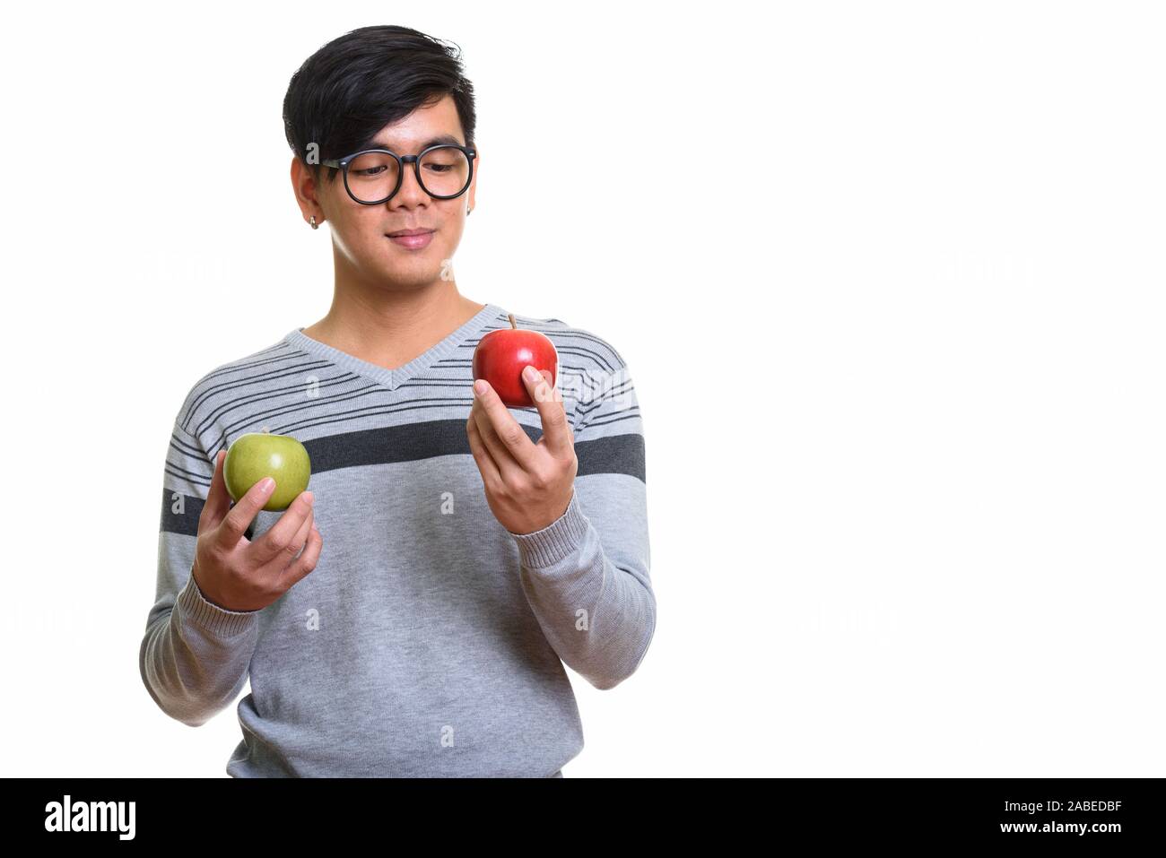 Studio shot of handsome Asian man looking at red apple et tout en Banque D'Images