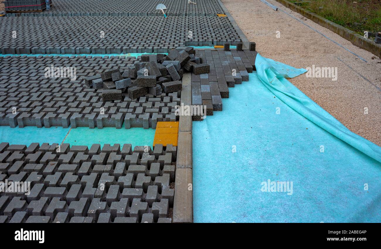 Mains d'un constructeur créant de nouveaux pavés plaçant soigneusement dans un poste sur une base de sol ratissées et nivelé Banque D'Images