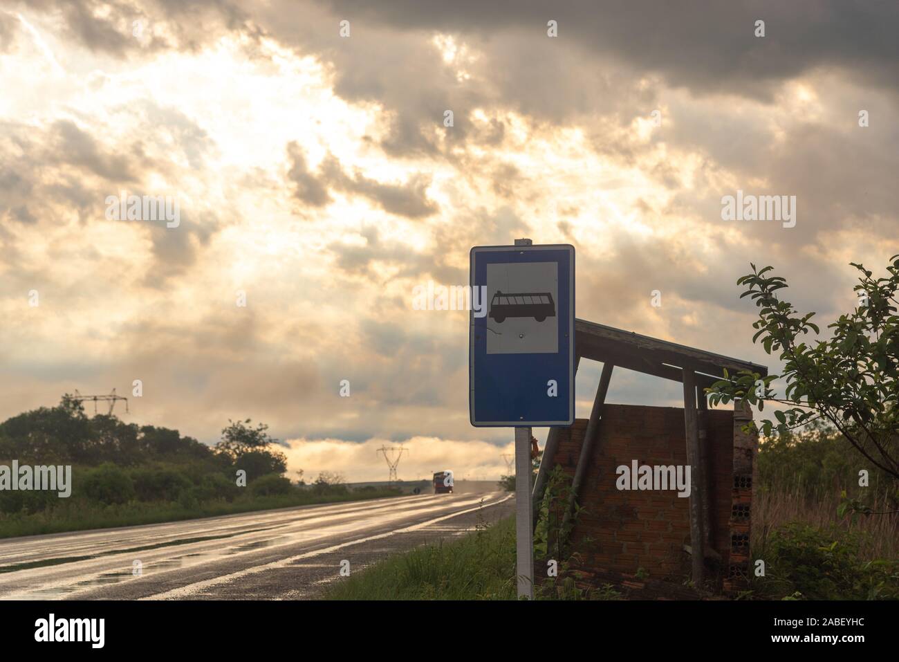 L 'arrêt de bus et d'orientation pour l'autoroute humide de pluie fraîchement tombée. Dans l'arrière-plan, la silhouette d'un camion traversant la route. Banque D'Images