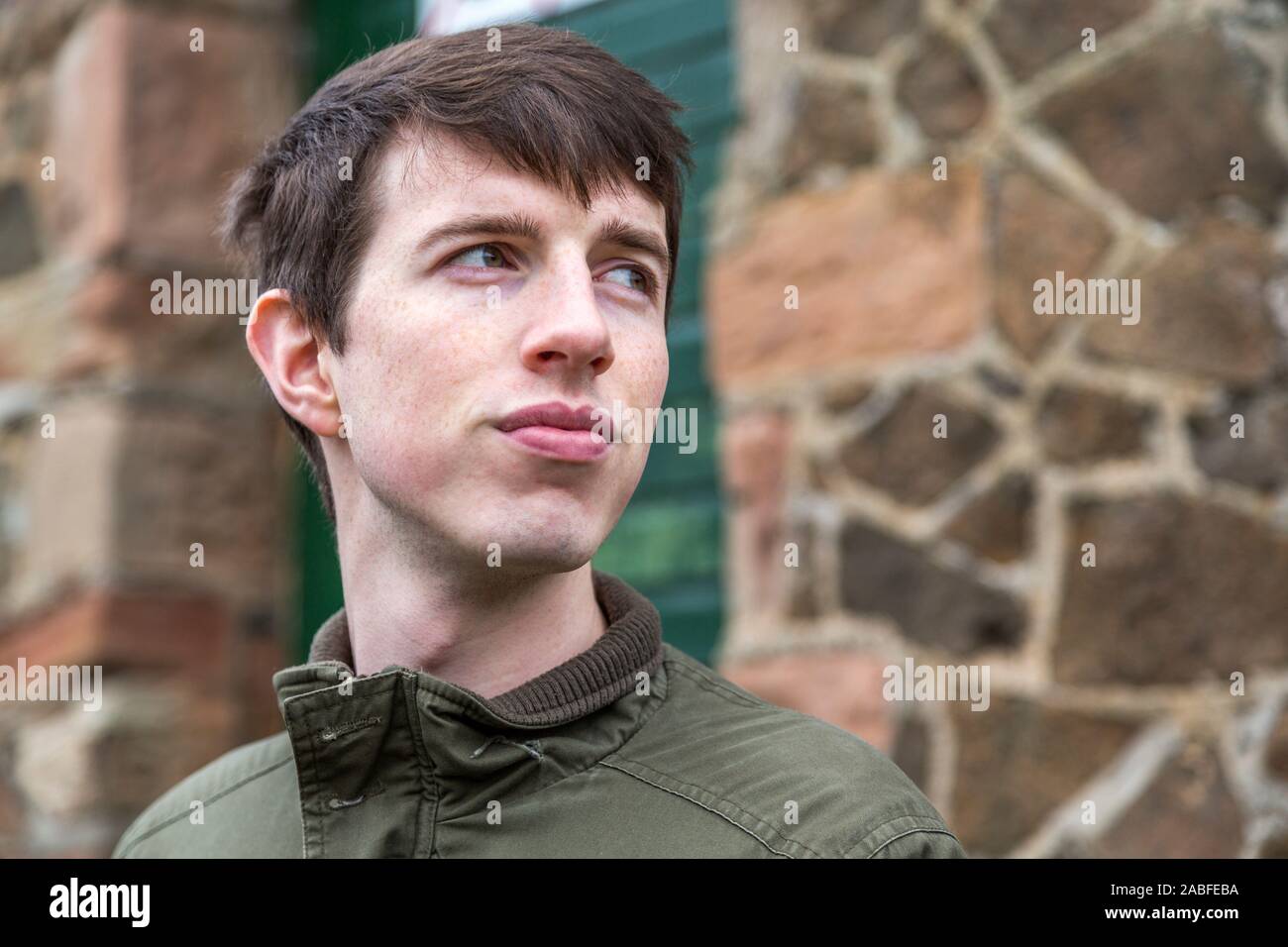 Close up d'un beau jeune homme dans la fin de l'adolescence ou au début de la vingtaine à la recherche dans la distance avec une forte expression optimiste. Banque D'Images