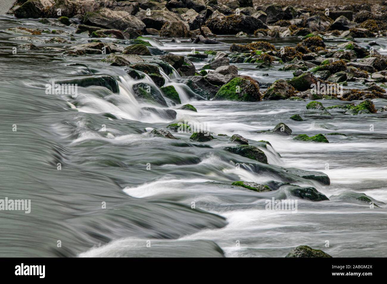 L'exposition longue comme le fleuve Meavy coule sur des roches en Lopwell Weir, Plymouth, Devon Banque D'Images